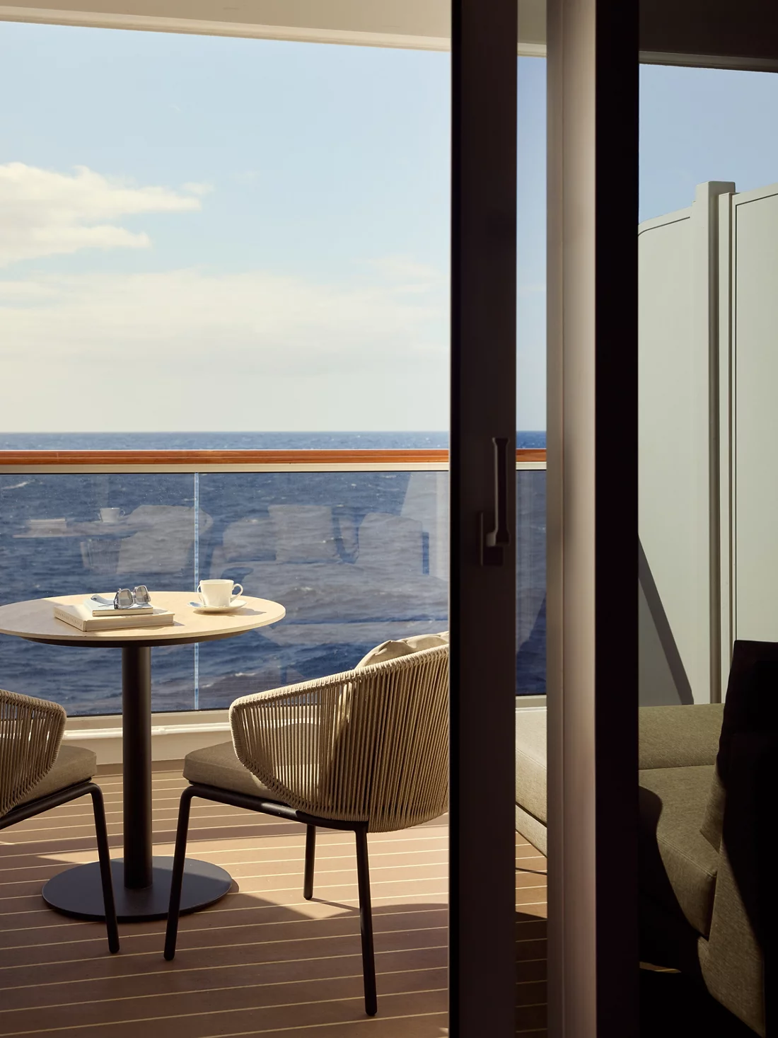 Café e um livro sobre a mesa de um terraço com vista para o mar