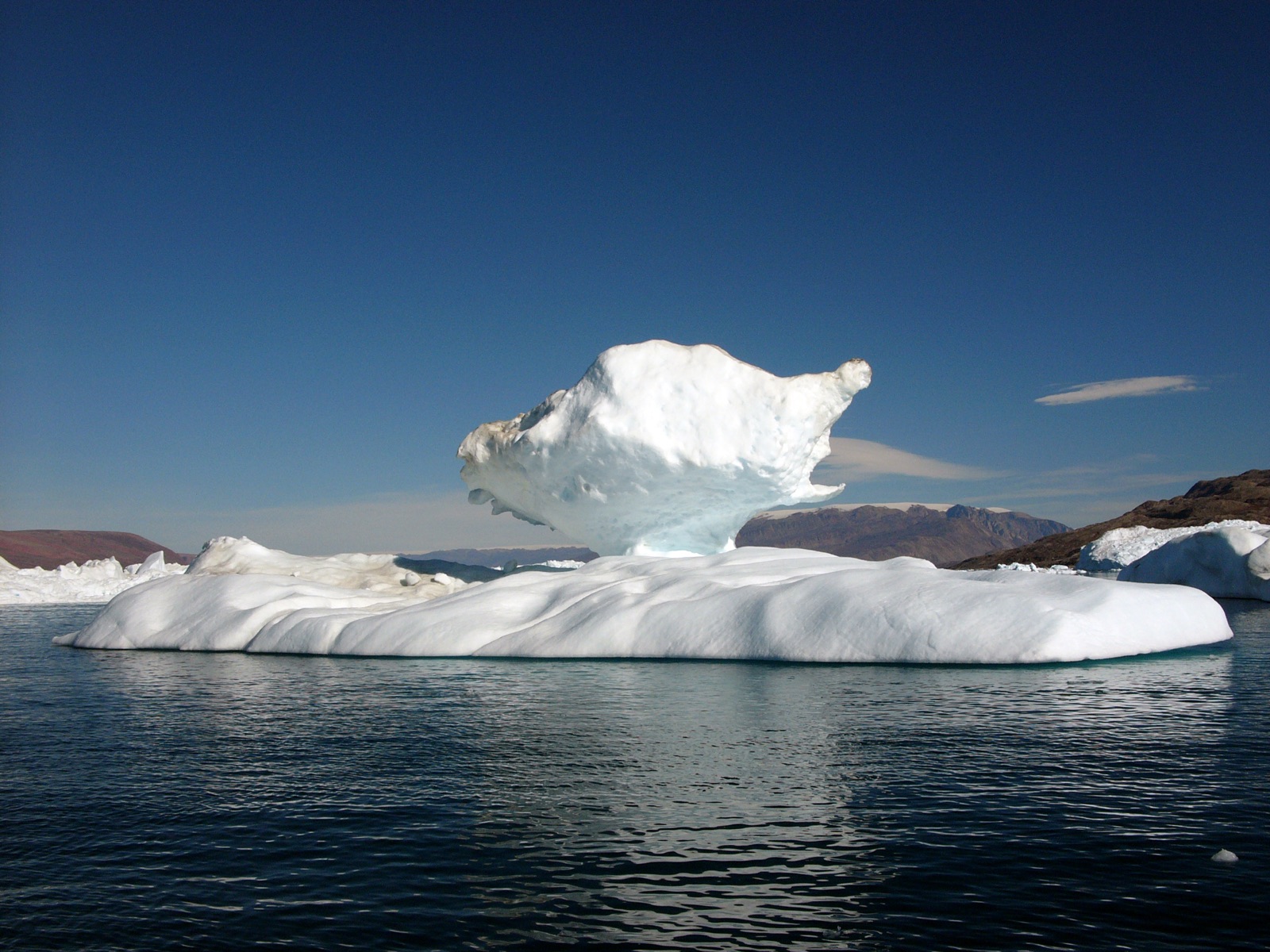 White iceberg floating in Greenland fjord under blue sky
